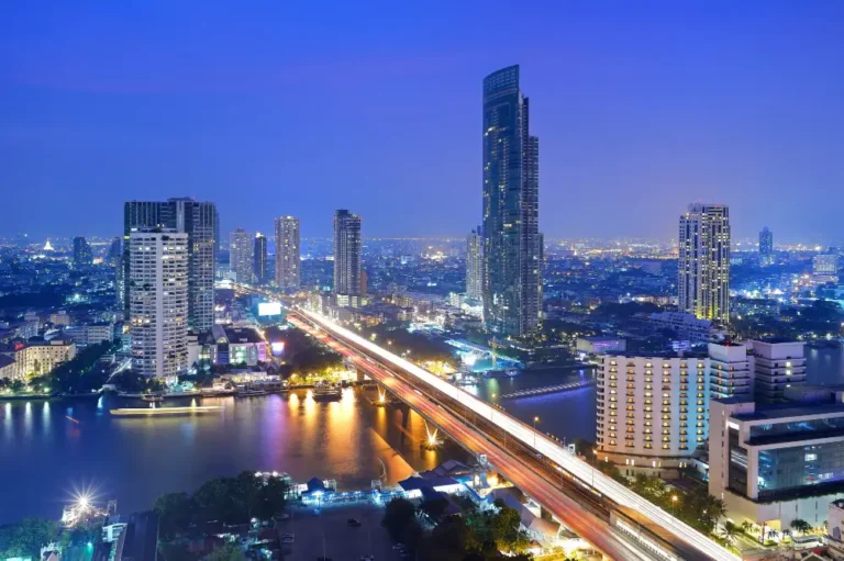 Bangkok's illuminated skyline and expressway by the river at night