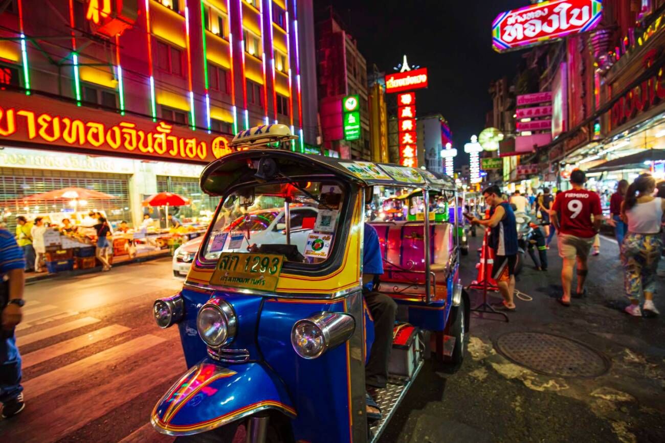 The iconic tuktuk, a popular transport mode, navigates through Bangkok's lively Chinatown night street food market in Thailand.