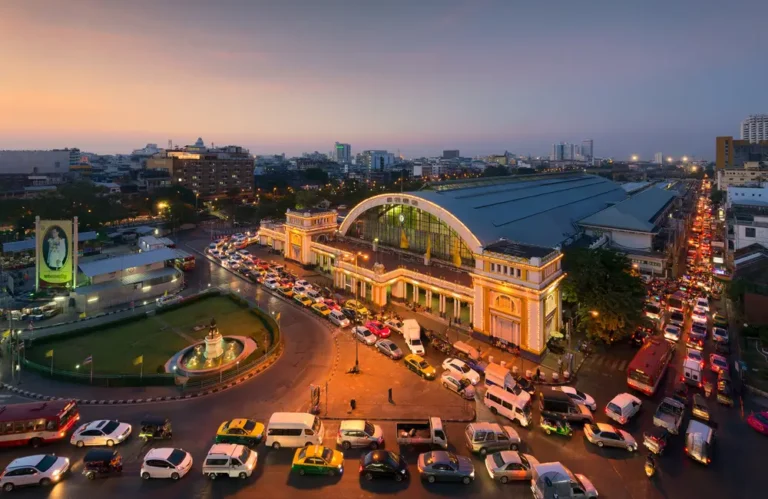 Twilight over Bangkok's Hua Lamphong Station with heavy traffic and glowing city lights